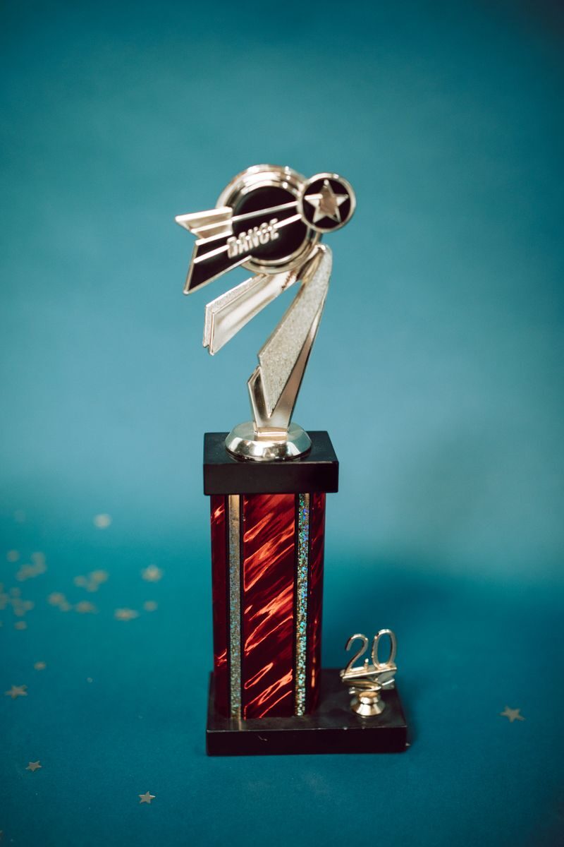 Silver and red dance trophy on blue background with stars and '20'.