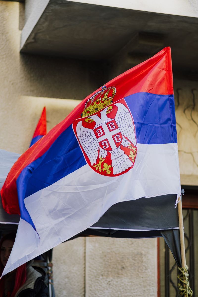 Close-up of a waving Serbian flag against urban backdrop in Belgrade city.