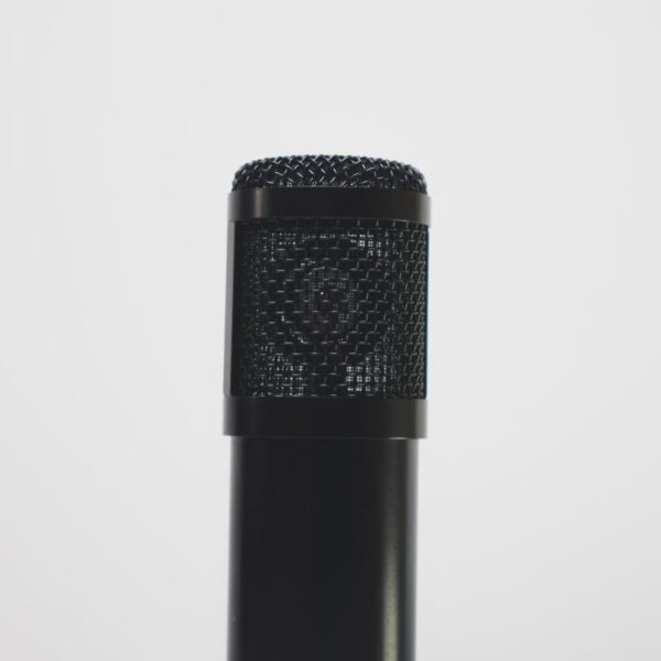Close-up of a black microphone against a white backdrop, perfect for audio recording themes.