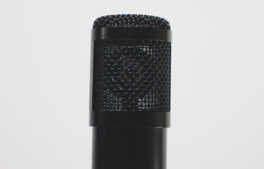 Close-up of a black microphone against a white backdrop, perfect for audio recording themes.