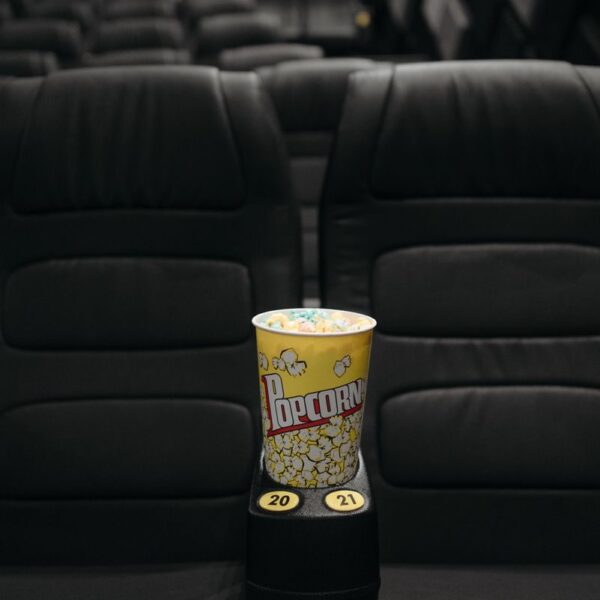 Close-up of popcorn bucket on empty cinema seats in a theater.