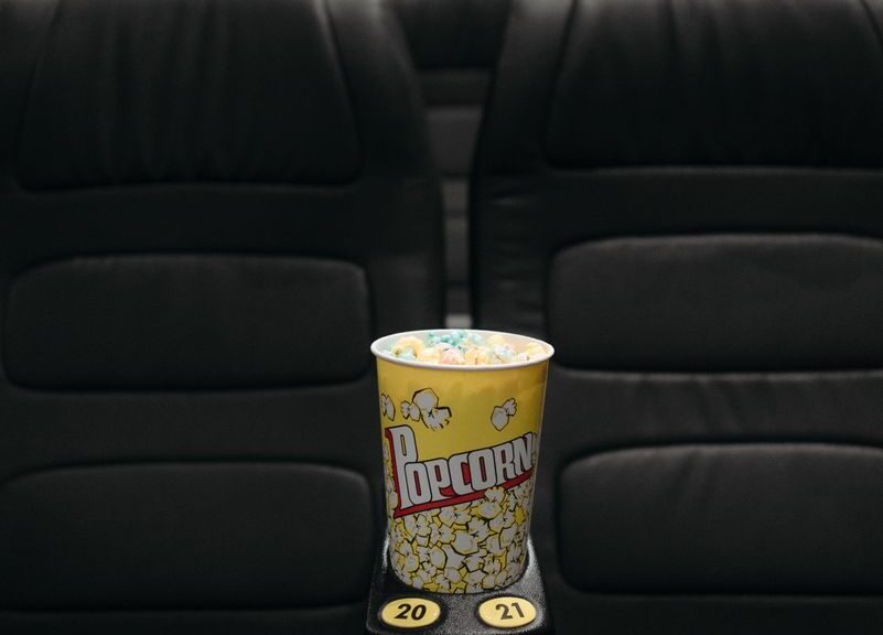 Close-up of popcorn bucket on empty cinema seats in a theater.