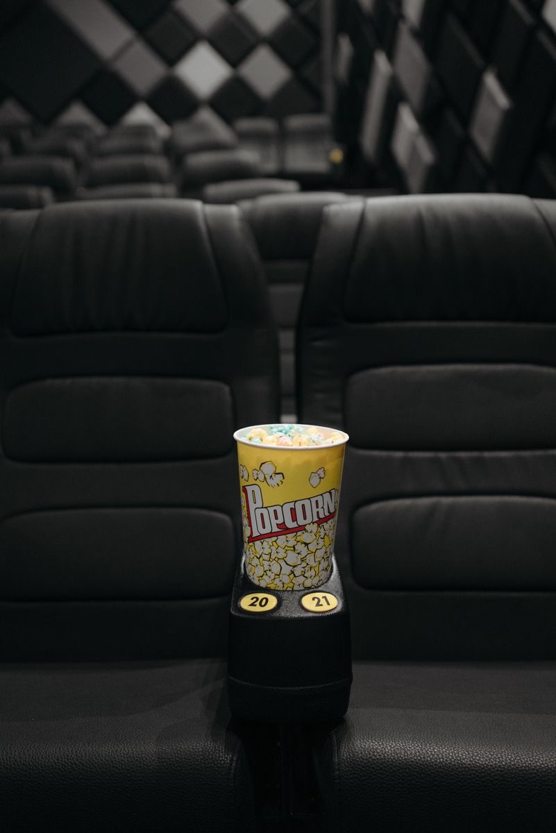 Close-up of popcorn bucket on empty cinema seats in a theater.