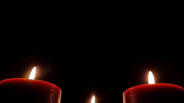 Moody and serene image of three red candles burning softly in the dark.