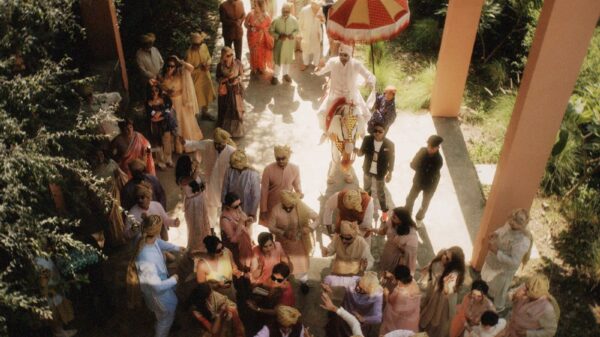 Vibrant Indian wedding procession with a groom on a decorated horse surrounded by colorful guests.
